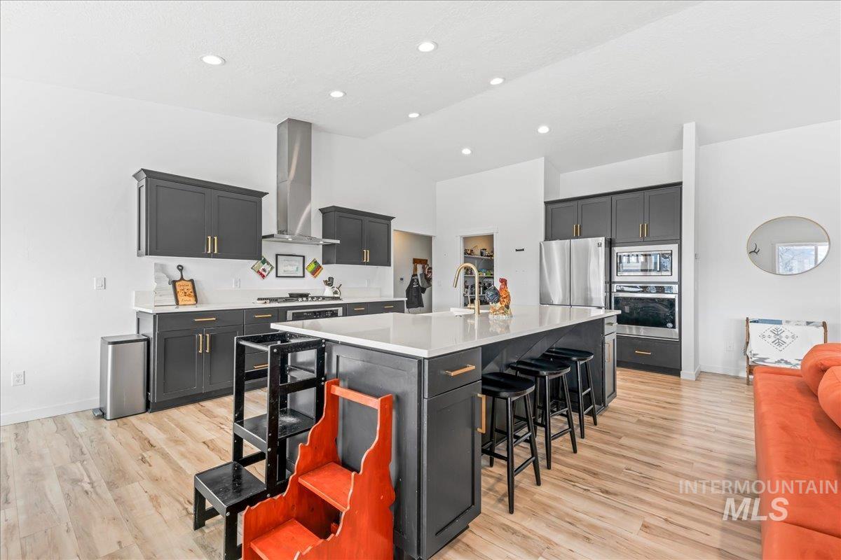 8843 Highway 78 Marsing, ID 83639 - Photo 18 of 48 Kitchen with light wood-style floors, a kitchen breakfast bar, stainless steel appliances, a spacious island, and lofted ceiling