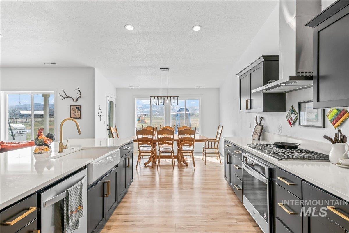 8843 Highway 78 Marsing, ID 83639 - Photo 19 of 48 Kitchen with light stone counters, stainless steel appliances, light wood-style flooring, hanging light fixtures, and a textured ceiling