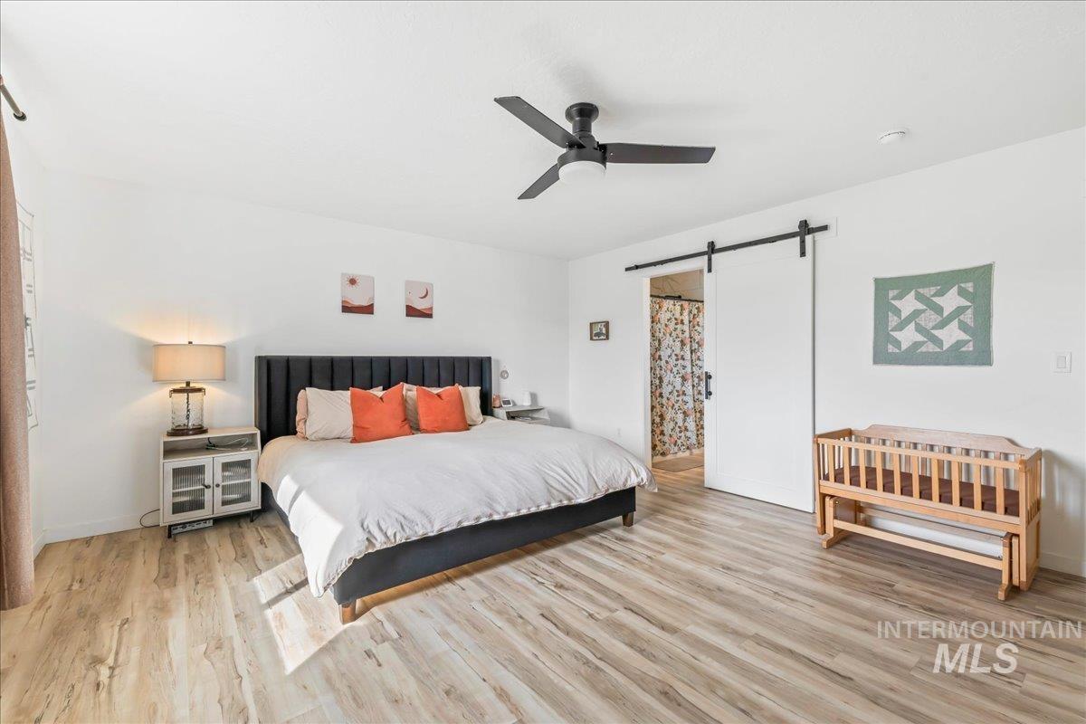 8843 Highway 78 Marsing, ID 83639 - Photo 24 of 48 Bedroom featuring a barn door, light wood-style flooring, and a ceiling fan