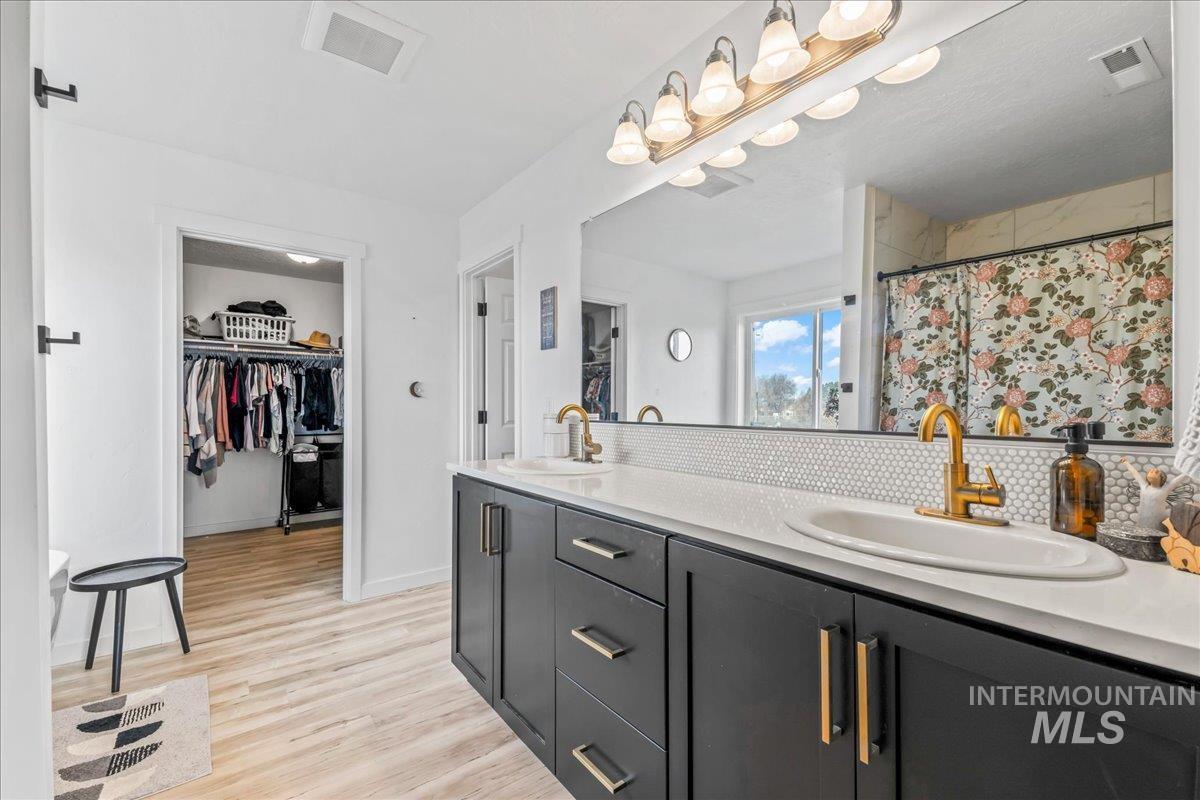 8843 Highway 78 Marsing, ID 83639 - Photo 26 of 48 Bathroom featuring double vanity, a shower with curtain, a spacious closet, tasteful backsplash, and light wood-type flooring