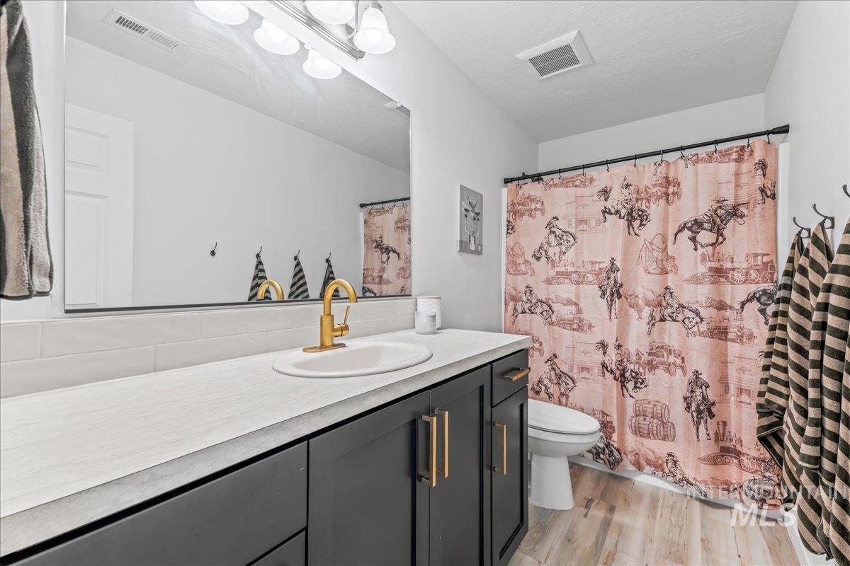 8843 Highway 78 Marsing, ID 83639 - Photo 32 of 48 Bathroom featuring vanity, light wood-style flooring, curtained shower, and a textured ceiling