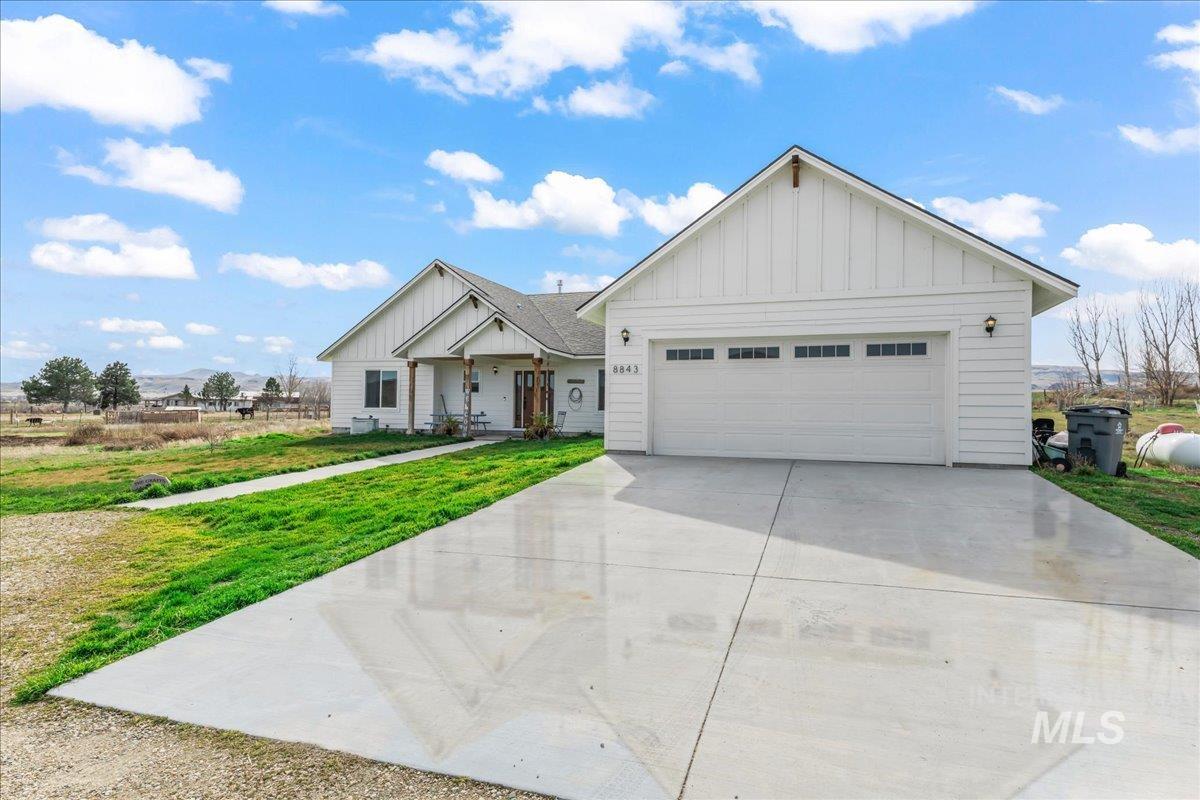 8843 Highway 78 Marsing, ID 83639 - Photo 4 of 48 View of front of home featuring board and batten siding, concrete driveway, a front yard, and an attached garage
