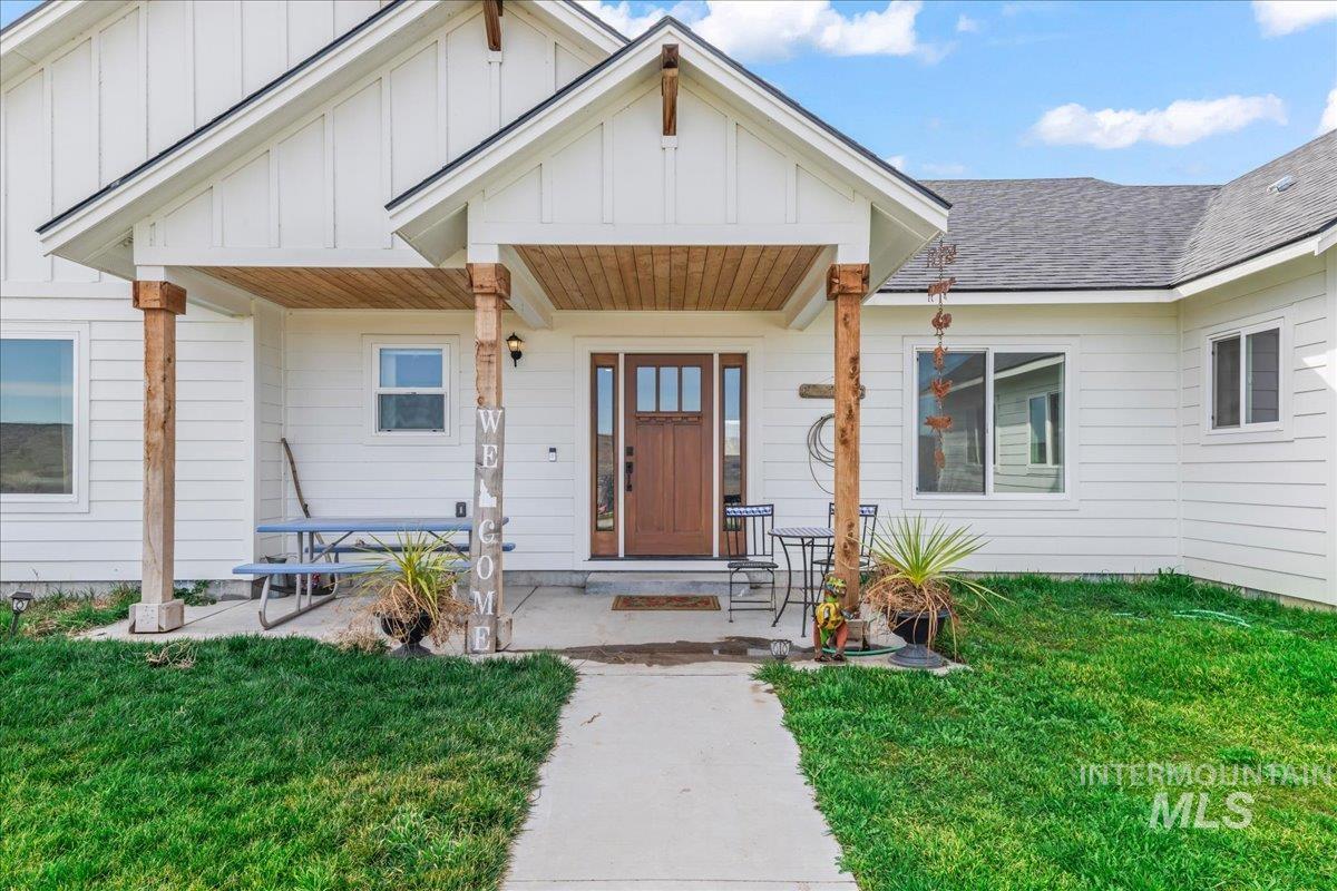 8843 Highway 78 Marsing, ID 83639 - Photo 5 of 48 View of exterior entry featuring board and batten siding, a porch, a yard, and roof with shingles