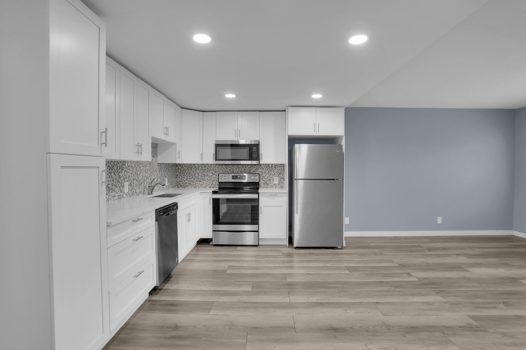 104 Mansfield C, Unit C Boca Raton, FL 33434 - Photo 6 of 40 a kitchen with a refrigerator and white cabinets