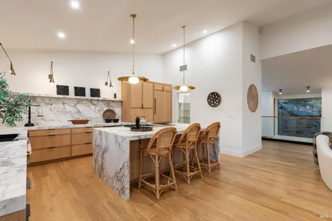 a kitchen with a stove a sink a kitchen island a couch and a flat screen tv