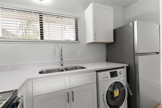 a kitchen with stainless steel appliances granite countertop a sink a refrigerator and a window