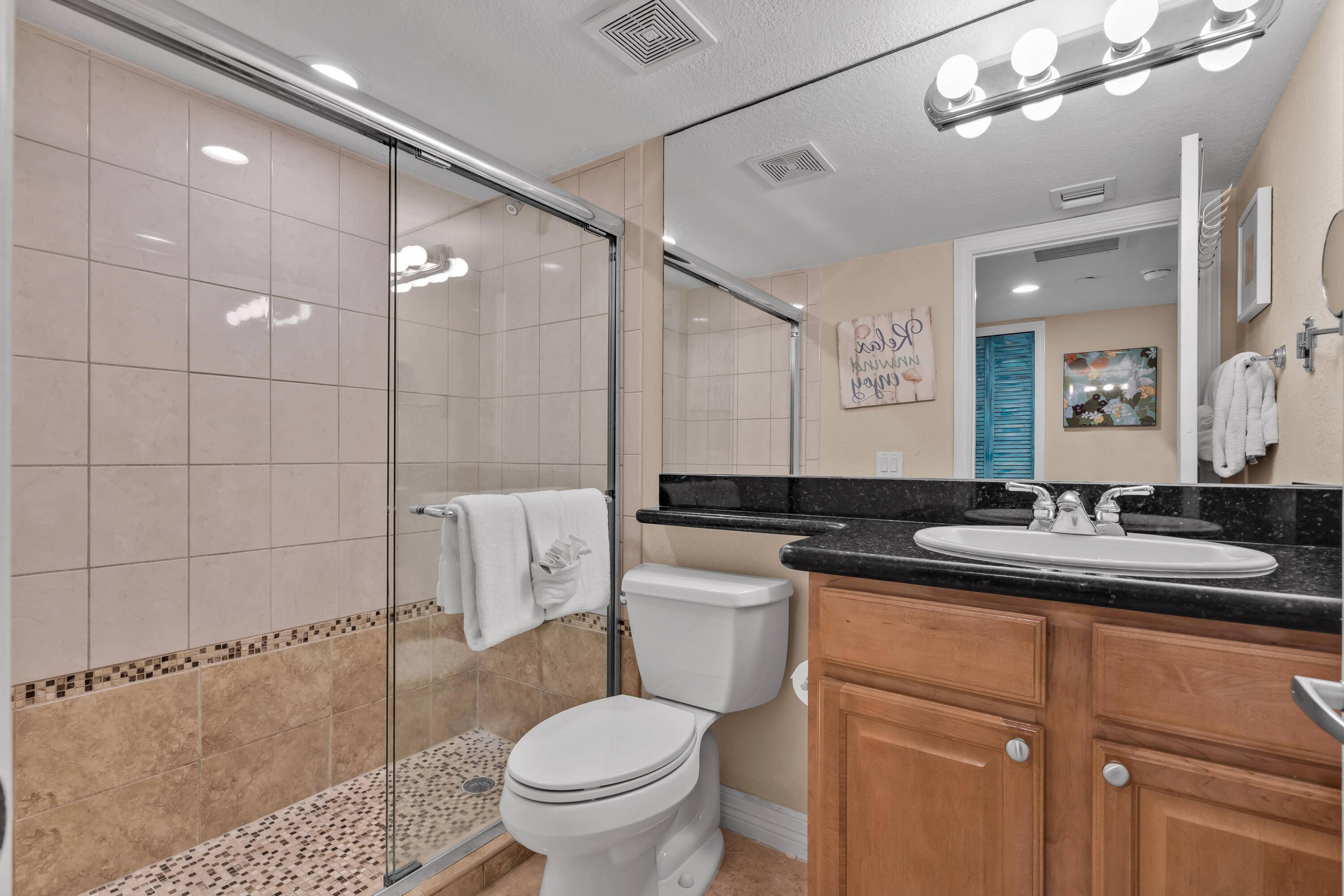 97501 Overseas Highway, Unit 607 Key Largo, FL 33037 - Photo 24 of 73 a bathroom with a granite countertop sink a toilet a mirror and shower