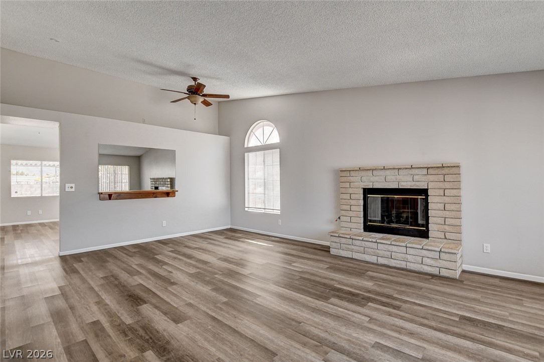 6209 Warm River Road Las Vegas, NV 89108 - Photo 5 of 39 A generous living room with sleek wood flooring and a classic brick fireplace provides an inviting gathering space.