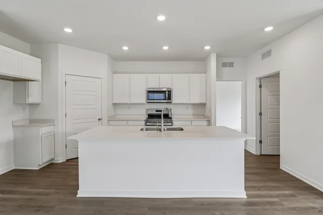 a large white kitchen with wooden floor and a refrigerator
