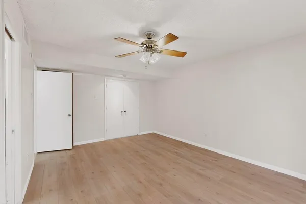 a view of a room with wooden floor and a ceiling fan
