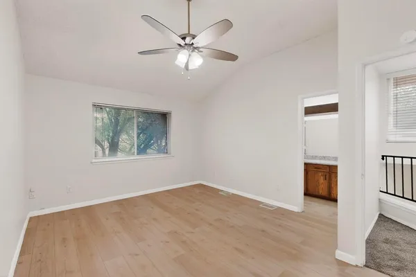 a view of an empty room with a window and wooden floor
