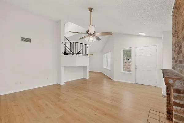 a view of empty room with wooden floor and ceiling fan