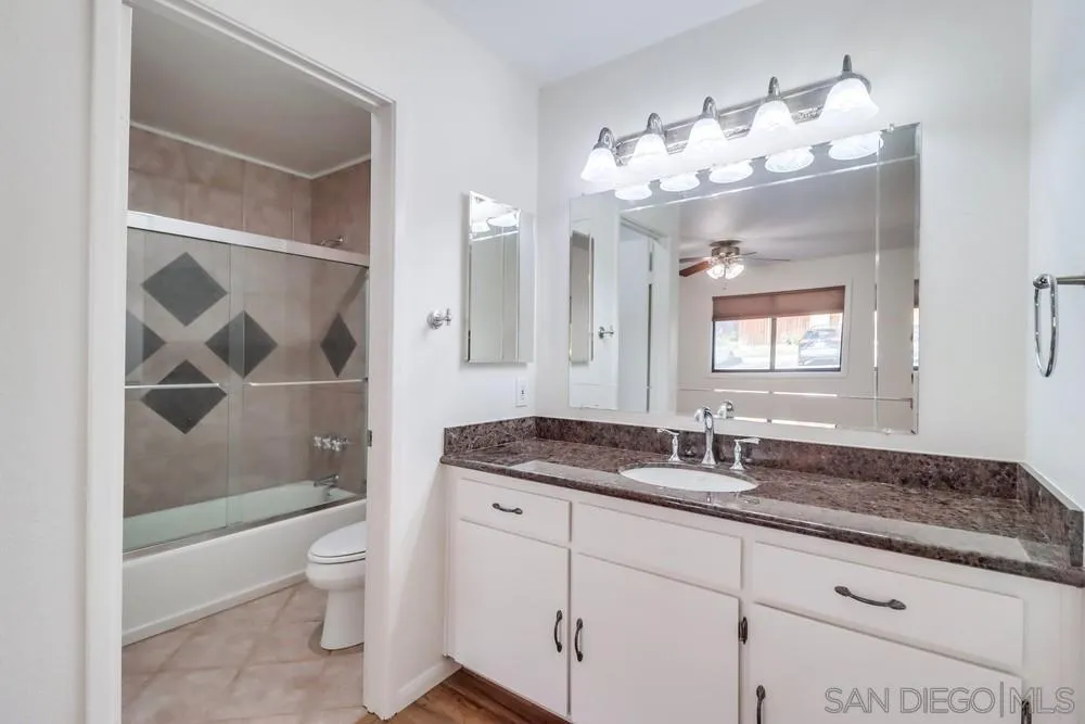 2157 Arnold Way, Unit 201 Alpine, CA 91901 - Photo 27 of 41 a bathroom with a granite countertop sink a toilet a mirror and shower