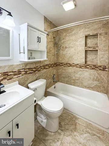 a bathroom with a granite countertop bathtub sink vanity mirror and toilet