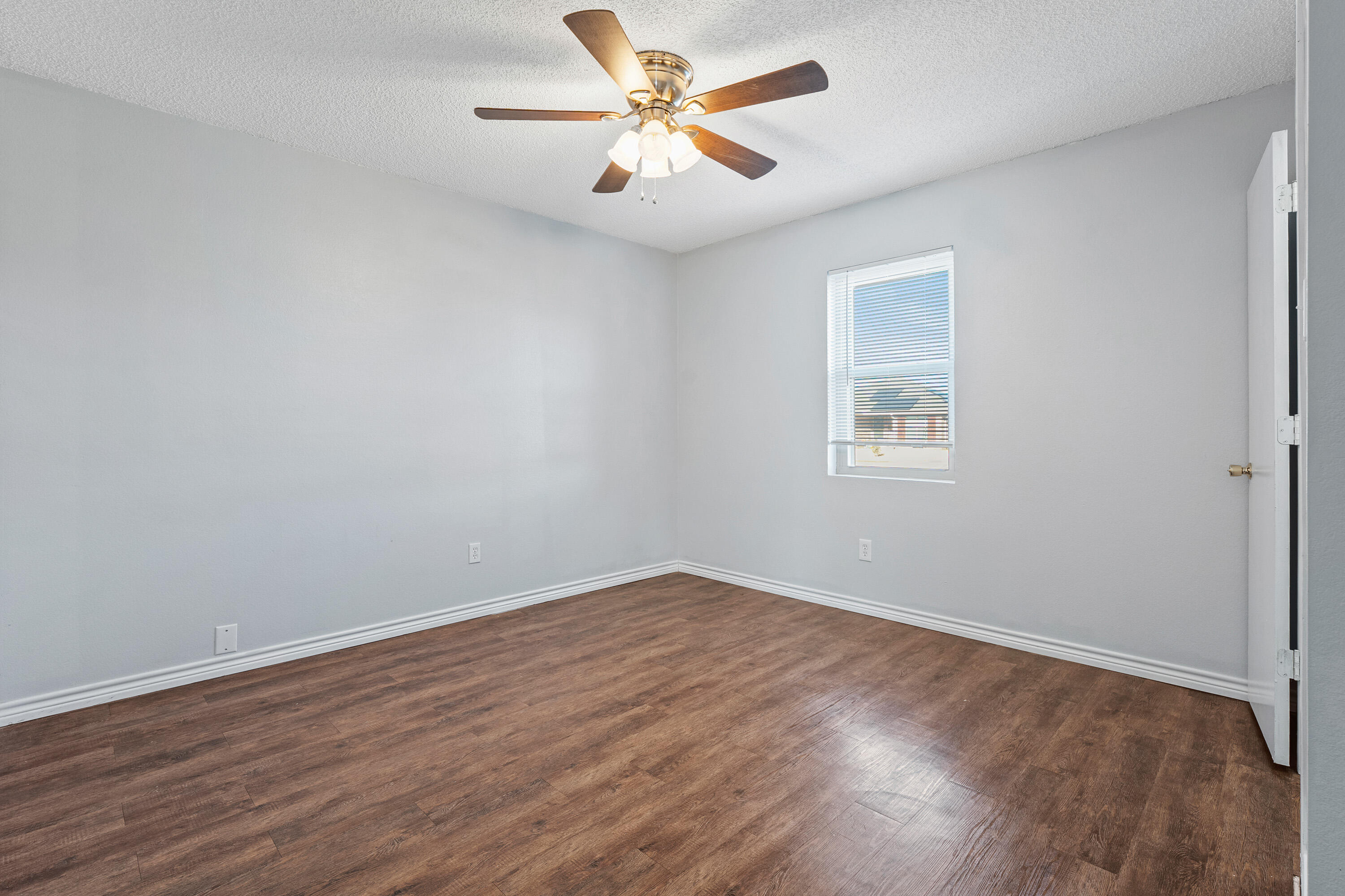 5705 Itasca Street Lubbock, TX 79416 - Photo 7 of 10 an empty room with wooden floor and a ceiling fan