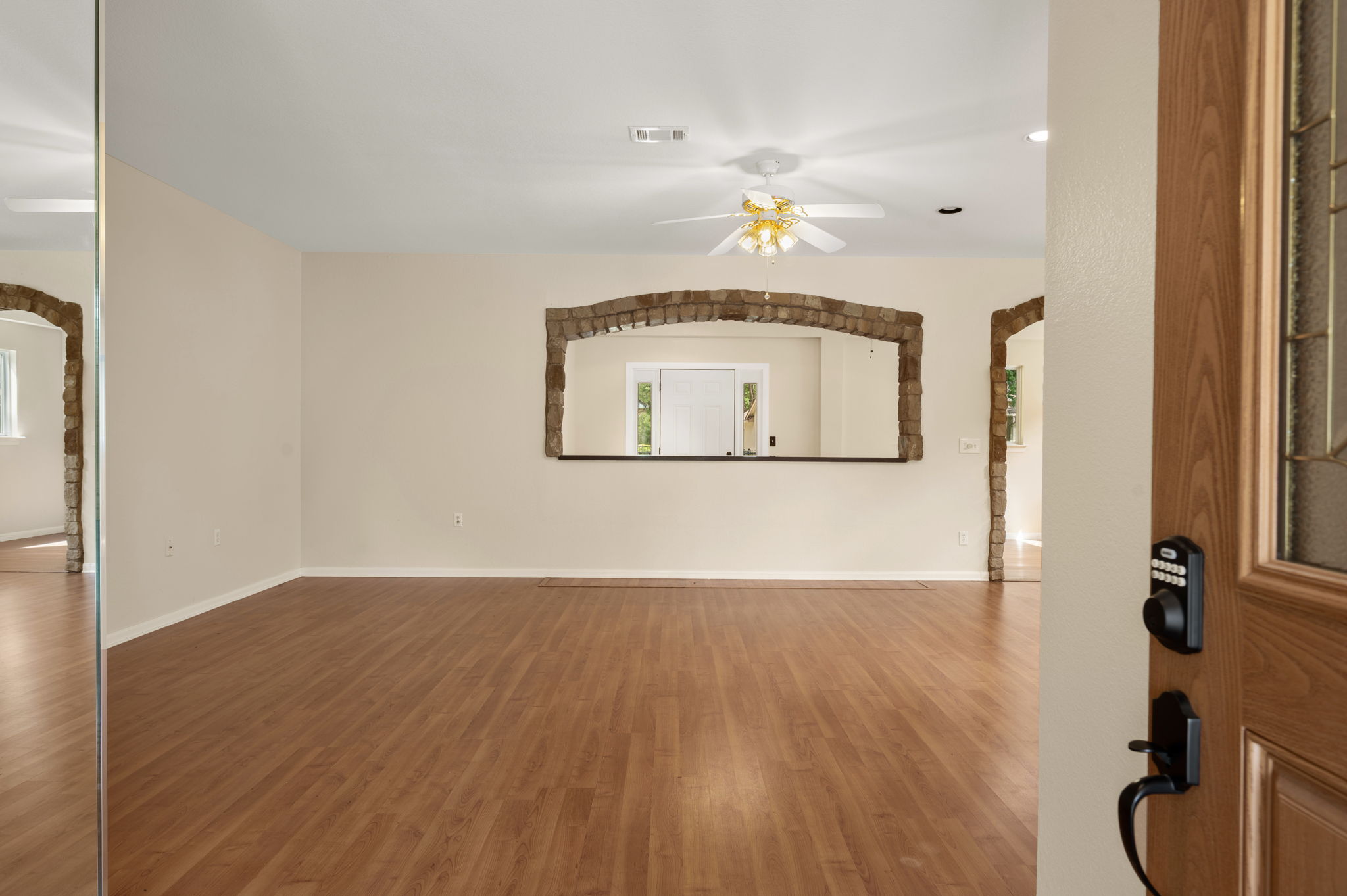 118 Bass Street Georgetown, TX 78633 - Photo 8 of 40 Rich hardwood-style flooring extends across an open-concept living area, highlighted by a decorative stone archway.