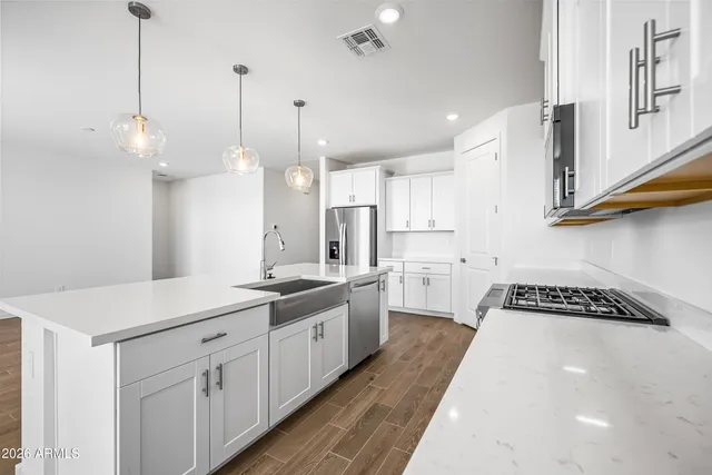 a open kitchen with stainless steel appliances granite countertop a sink a stove a refrigerator and white cabinets