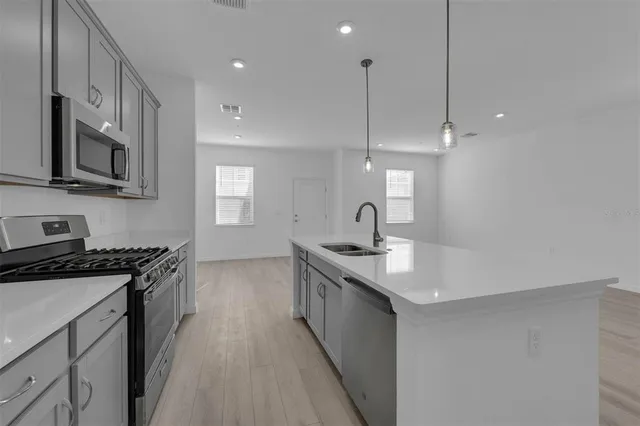 a kitchen with stainless steel appliances granite countertop a sink a stove and a wooden floors
