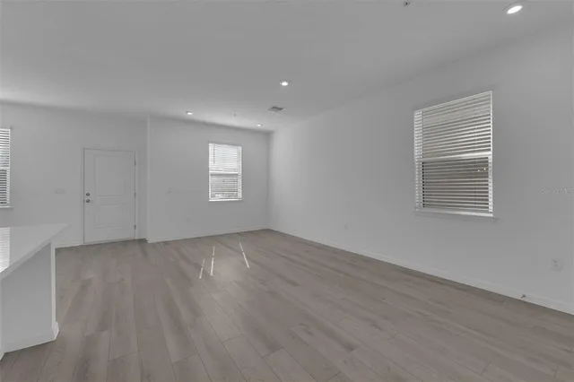 an empty room with wooden floor and window