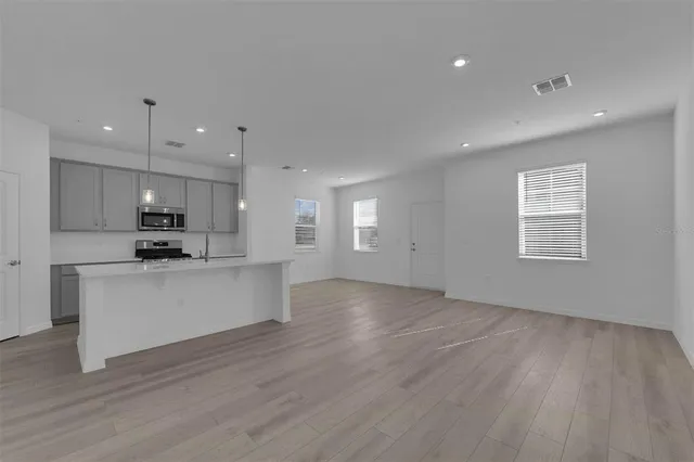 a view of kitchen with stainless steel appliances granite countertop a stove a sink a refrigerator white cabinets and wooden floor