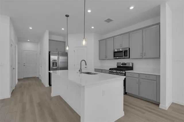 a kitchen with stainless steel appliances kitchen island a sink a stove a microwave and cabinets