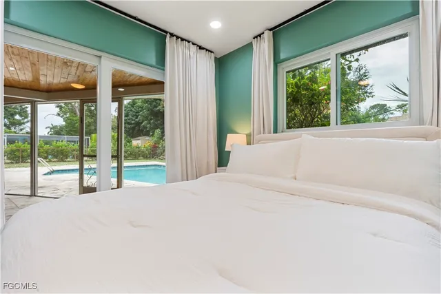 a large white bed sitting in a bedroom next to a window