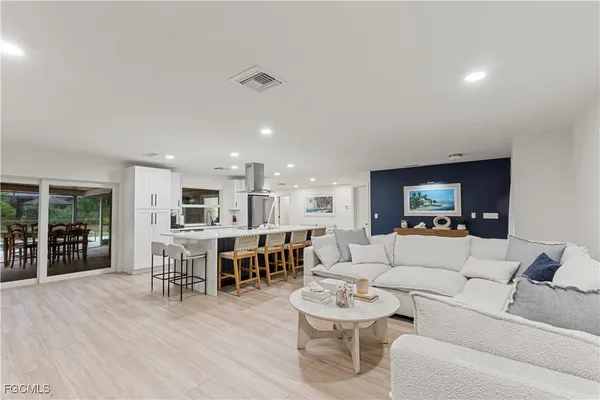 a living room with furniture kitchen view and a wooden floor
