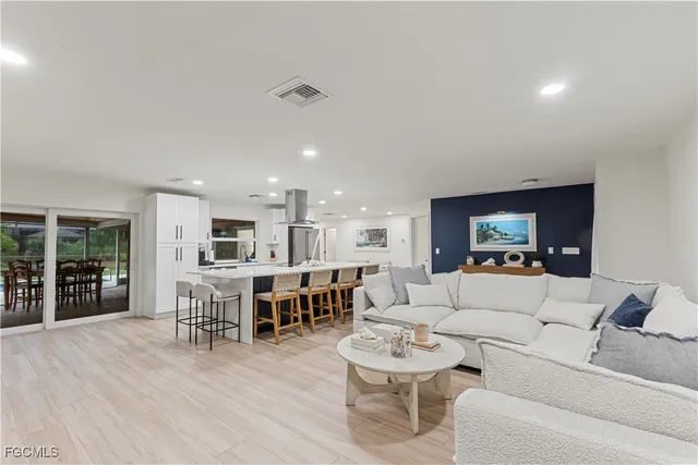 a living room with furniture kitchen view and a wooden floor