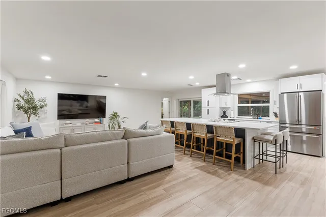 a open dining room with stainless steel appliances kitchen island granite countertop a table chairs and a large window
