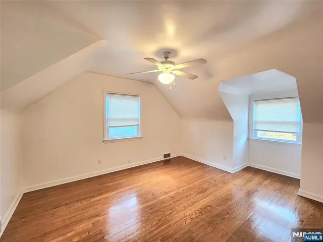 an empty room with wooden floor cabinet and windows