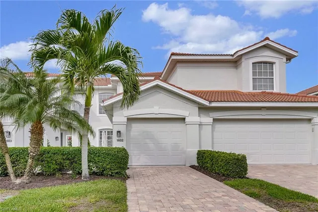 a view of a white house with a small yard and a large tree