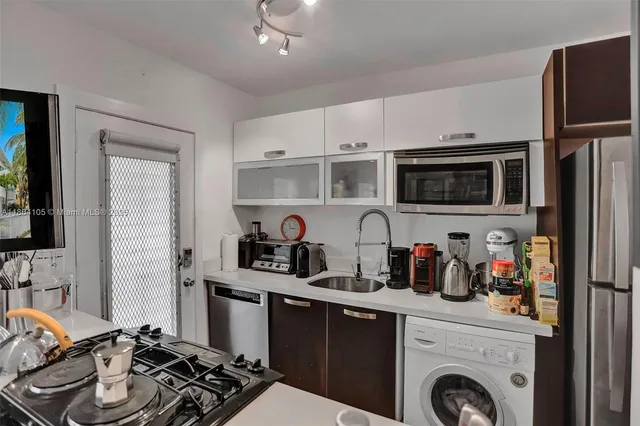 a kitchen with stainless steel appliances kitchen island granite countertop a sink and a refrigerator
