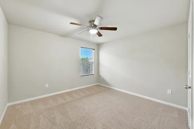 an empty room with window and a ceiling fan