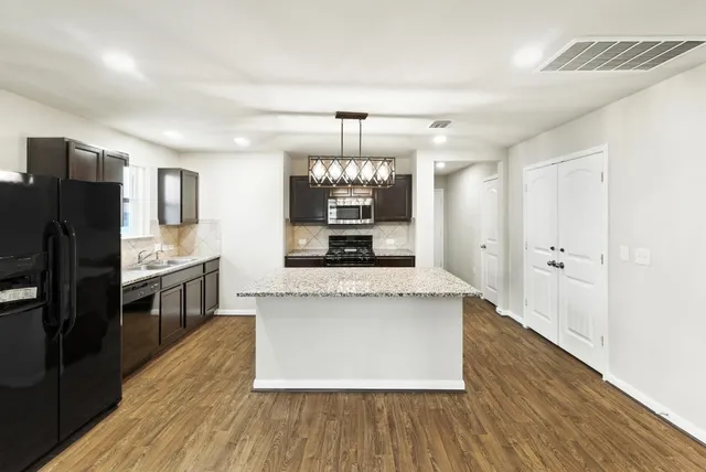 a large kitchen with stainless steel appliances a large counter top a sink and a refrigerator