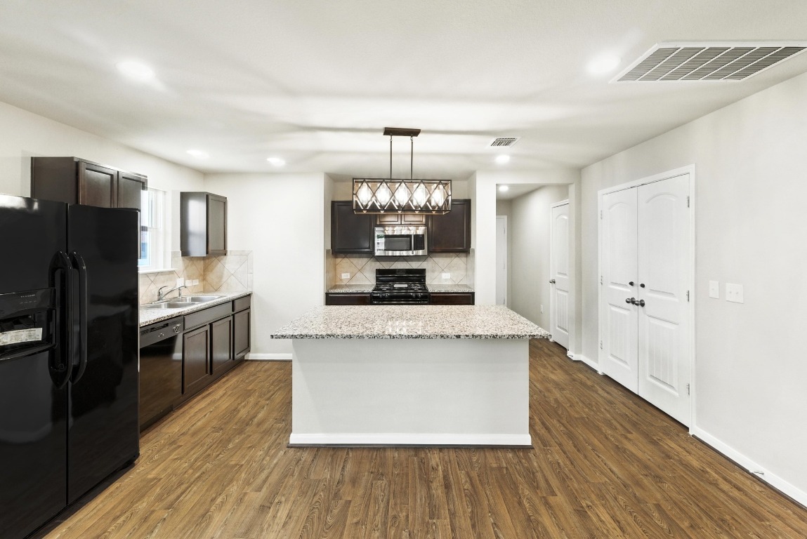 148 Alpha Kyle, TX 78640 - Photo 9 of 36 a large kitchen with stainless steel appliances a large counter top a sink and a refrigerator