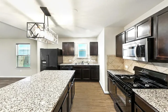 a large kitchen with stainless steel appliances granite countertop a stove and a sink