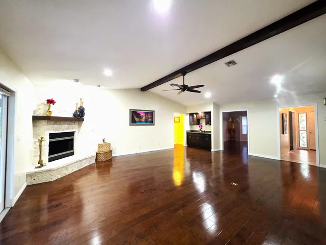 an empty room with wooden floor chandelier and windows