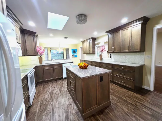 a kitchen with stainless steel appliances granite countertop a refrigerator a sink and a stove
