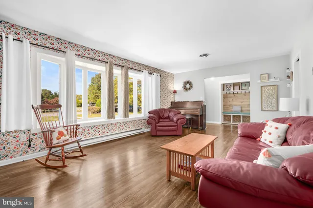 a living room with furniture large window and wooden floor