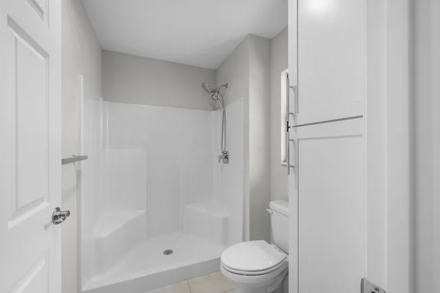 a bathroom with a shower a toilet and a glass door