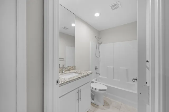 a bathroom with a granite countertop sink a toilet and shower