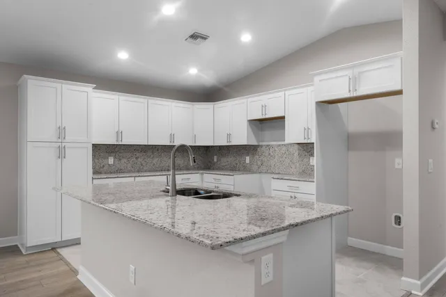 a kitchen with granite countertop a sink a center island stainless steel appliances and cabinets
