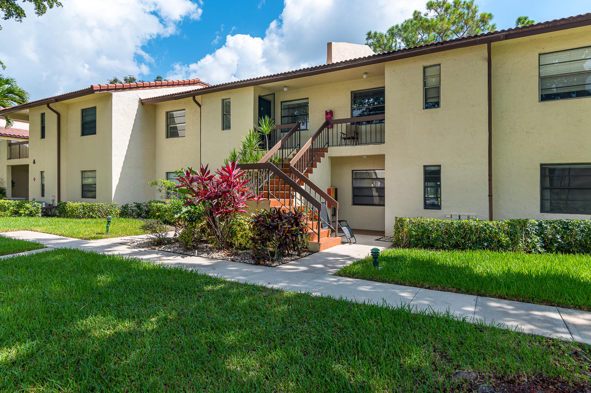 21856 Arriba Real, Unit 5E Boca Raton, FL 33433 - Photo 1 of 17 a front view of a house with a yard and potted plants