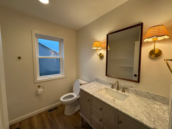 a bathroom with a granite countertop sink toilet and mirror
