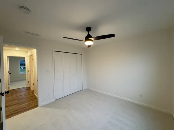 an empty room with closet and a ceiling fan