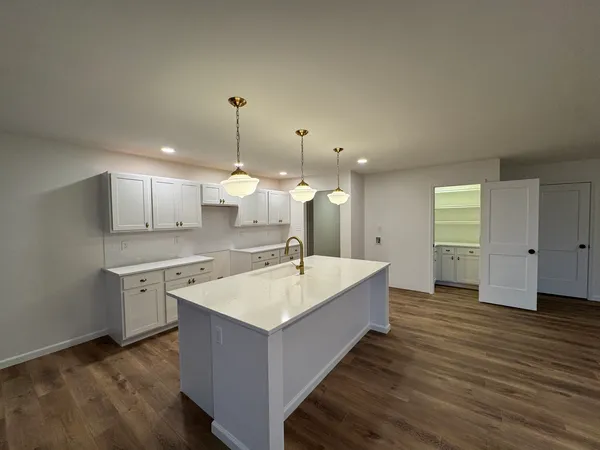 a large kitchen with kitchen island a sink dishwasher a stove and a refrigerator with wooden floor