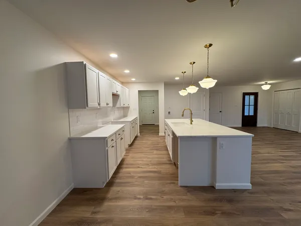 a large room with kitchen island a sink a center island and wooden floor