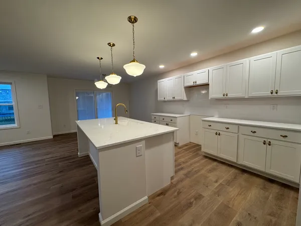 a kitchen with a sink a stove cabinets and wooden floor