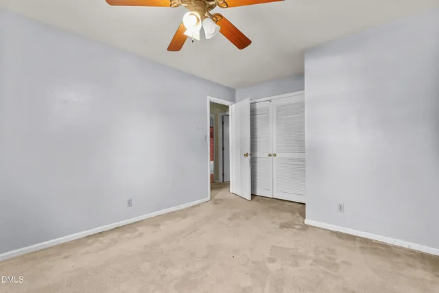 an empty room with a window and ceiling fan