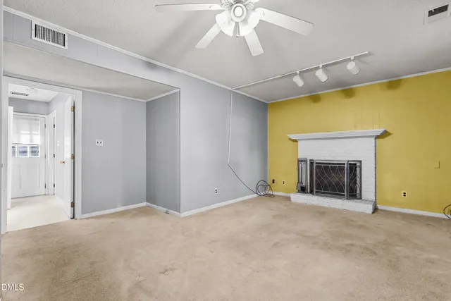 a view of an empty room with a fireplace and a ceiling fan